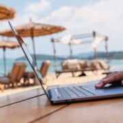 Digital nomad working from laptop outdoors at beach