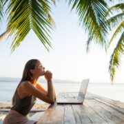 freelancer girl with a computer among tropical palm trees work on the island in sunset