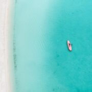 Drone photo of beach in Grace Bay, Providenciales, Turks and Caicos. The caribbean blue sea and underwater rocks can be seen, as well as some jet skies